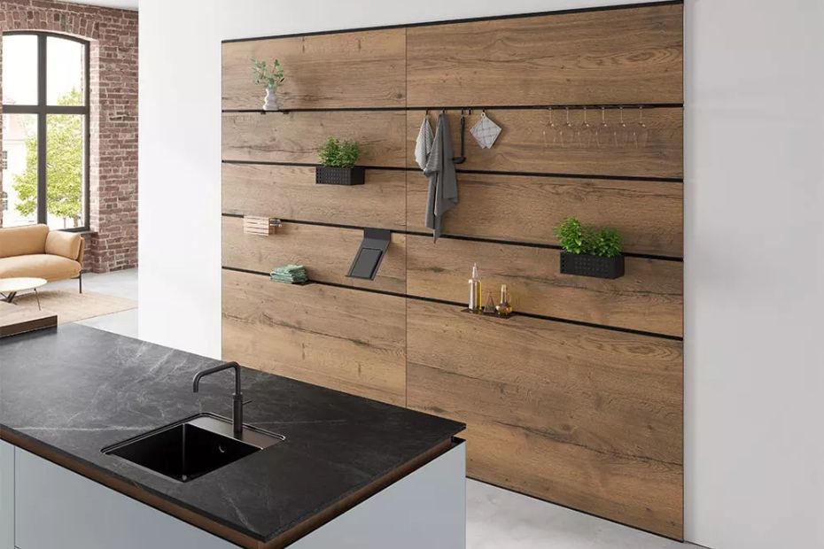 Holzverkleidete Wand mit eingelassenen schwarzen Profilleisten und flexiblen Ablagen und Haken.