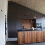 Moderne Küche mit dunkler Hochschrankwand, Holz-Kücheninsel und offenen Regalen